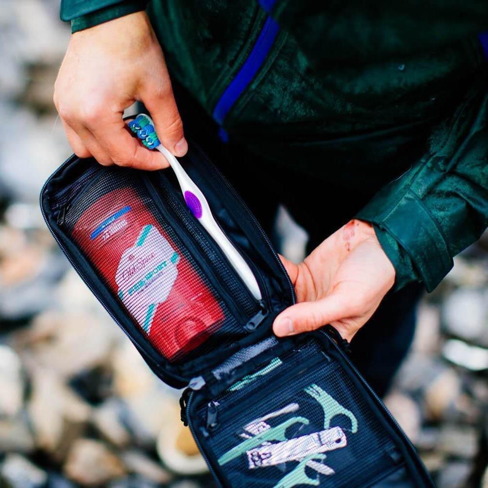 Garage Sale | V1 Explorer SLIM™ Toiletry Bag - Traveling Lighter - Gravel - Man holding Explorer Slim with toothbrush inside