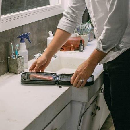 Garage Sale | V1 Explorer SLIM™ Toiletry Bag - Traveling Lighter - Gravel - Man unpacking Explorer SLIM™ Toiletry Bag in bathroom