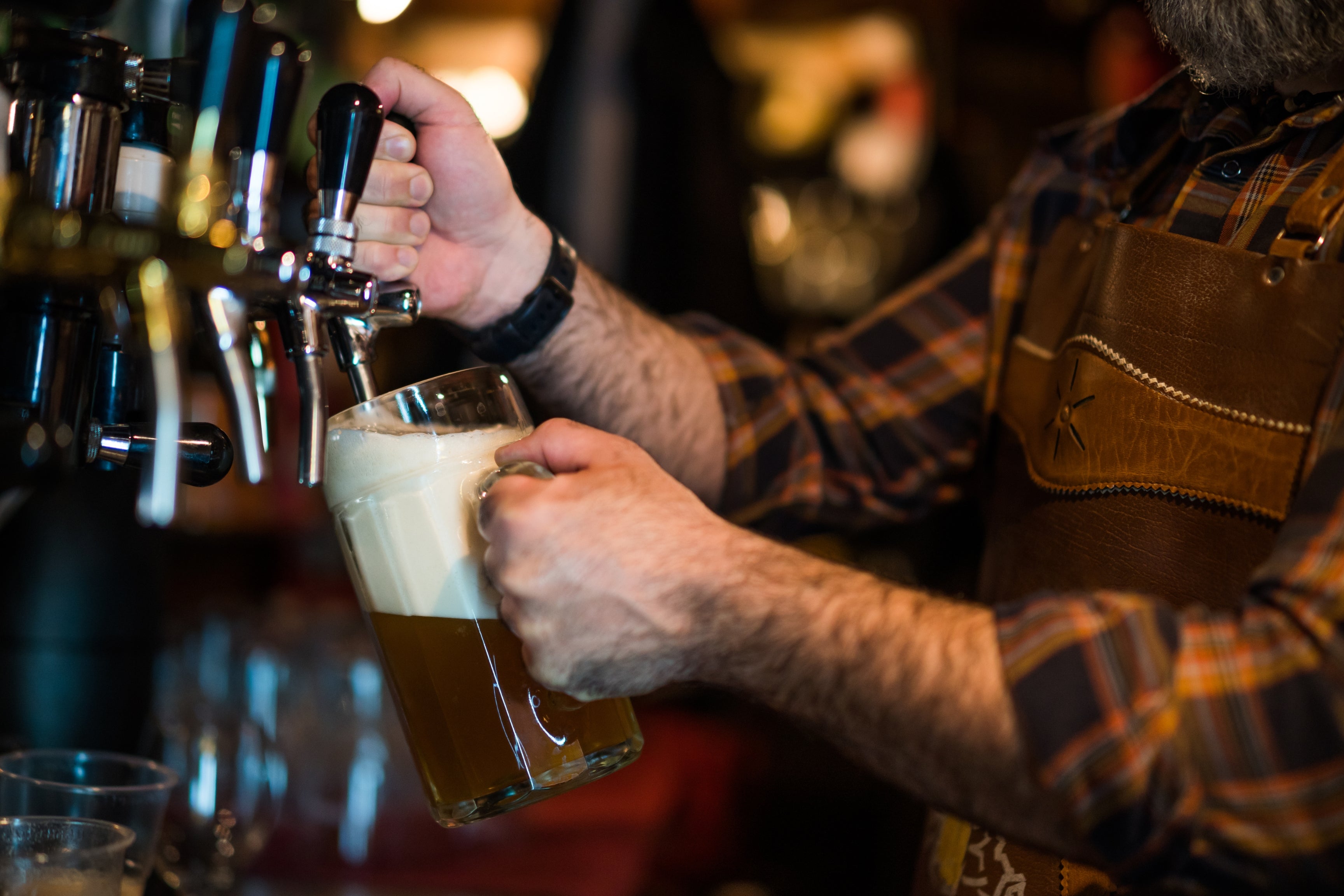 man in checkered shirt drafting beer from tap