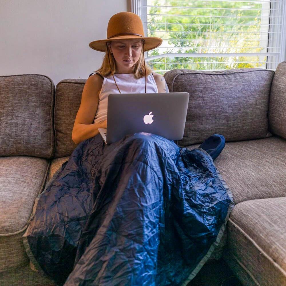 Woman using Blue Layover Travel Blanket while working on laptop